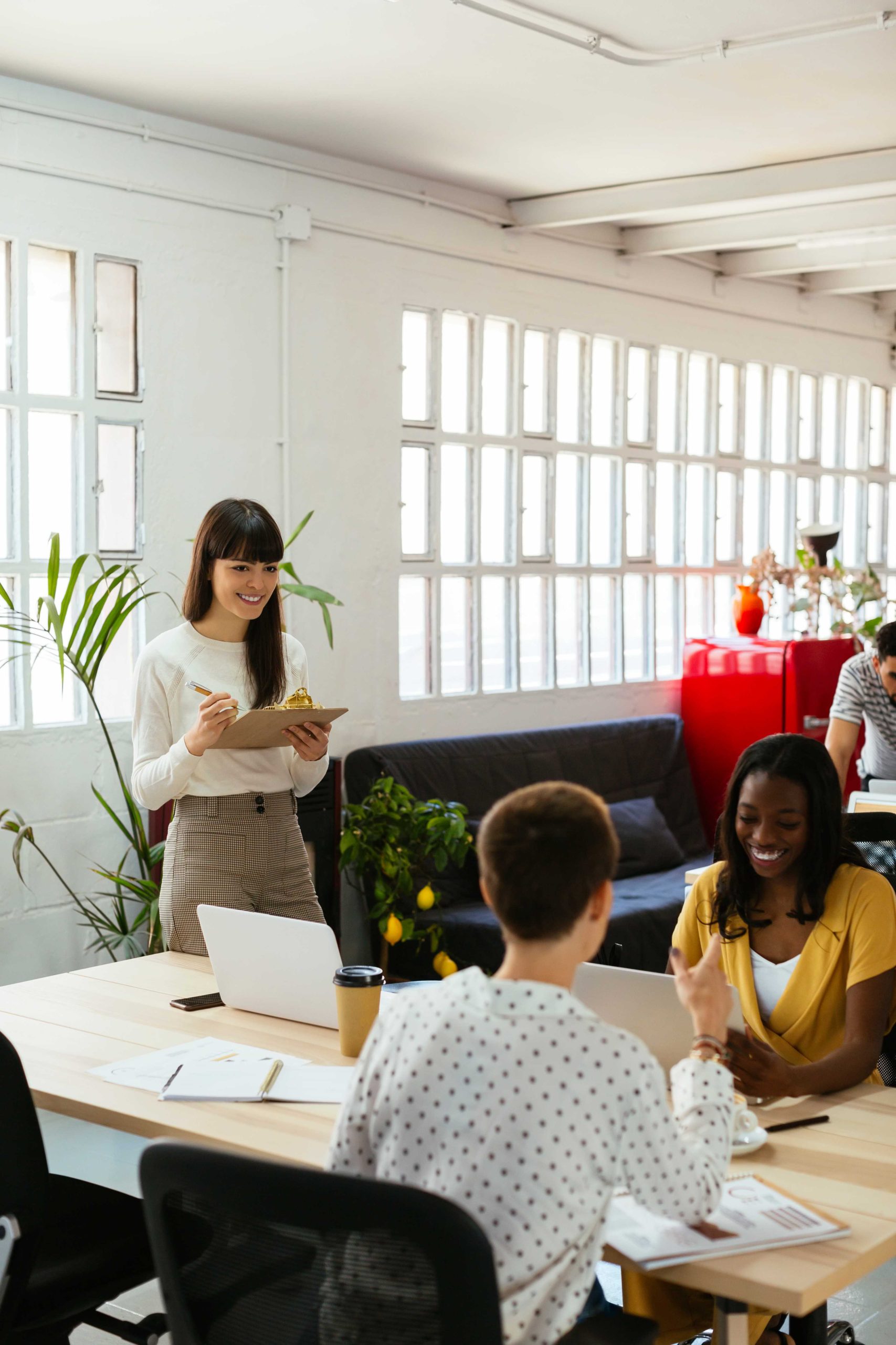 smiling-woman-with-clipboard-among-colleagues-in